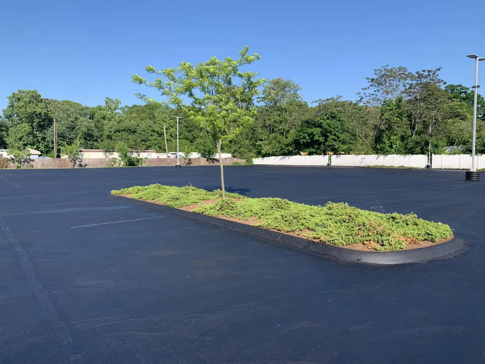 Freshly sealcoated commercial parking lot with landscaped island in Connecticut