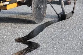Hot rubber crack filler being applied to a crack in asphalt pavement