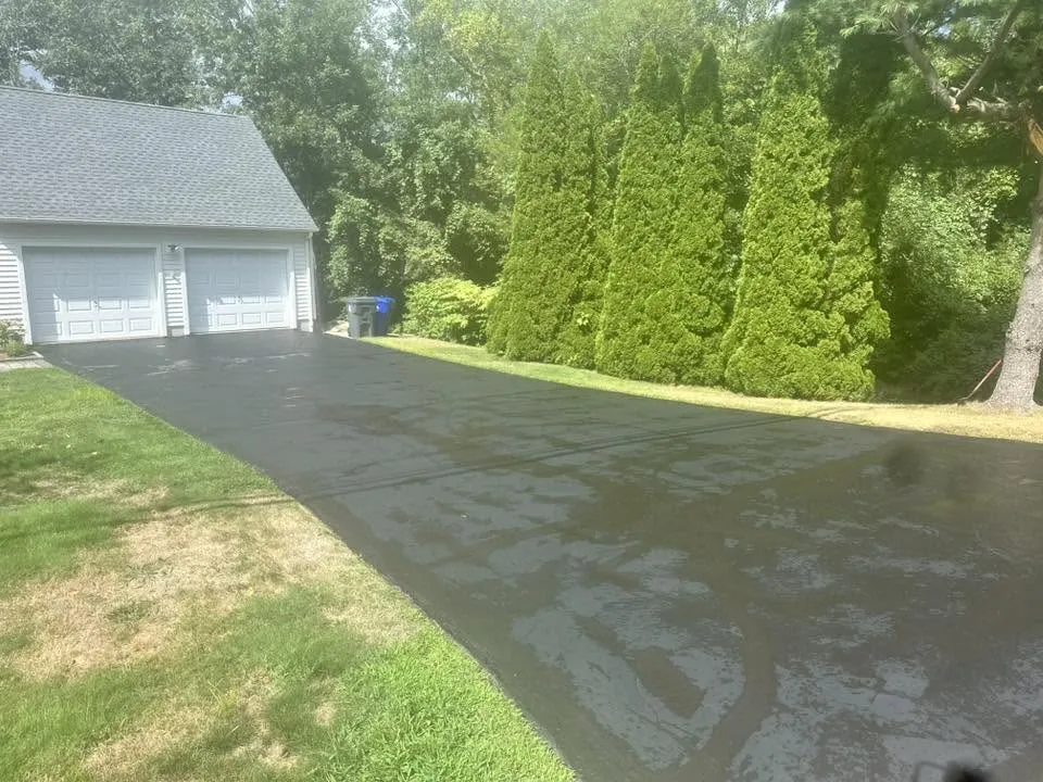 Freshly sealcoated residential driveway beside a home garage in Connecticut