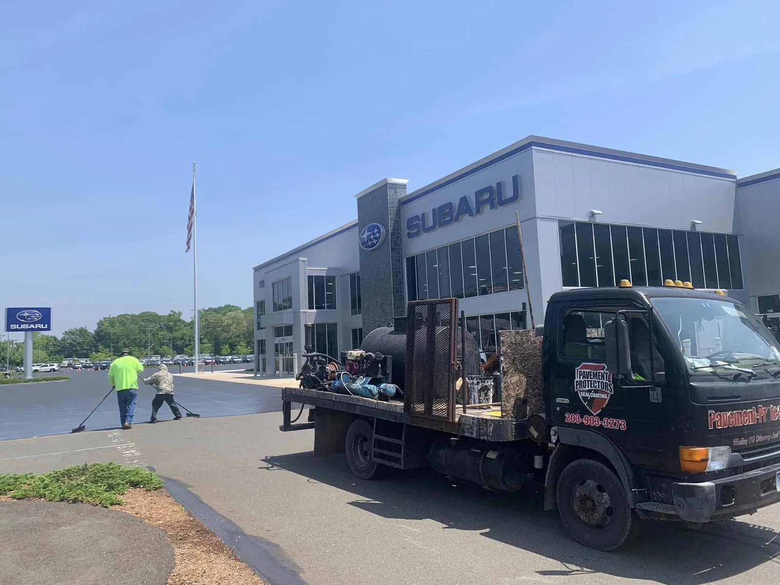 Sealcoating crew and Pavement Protectors truck at a Subaru dealership in Connecticut